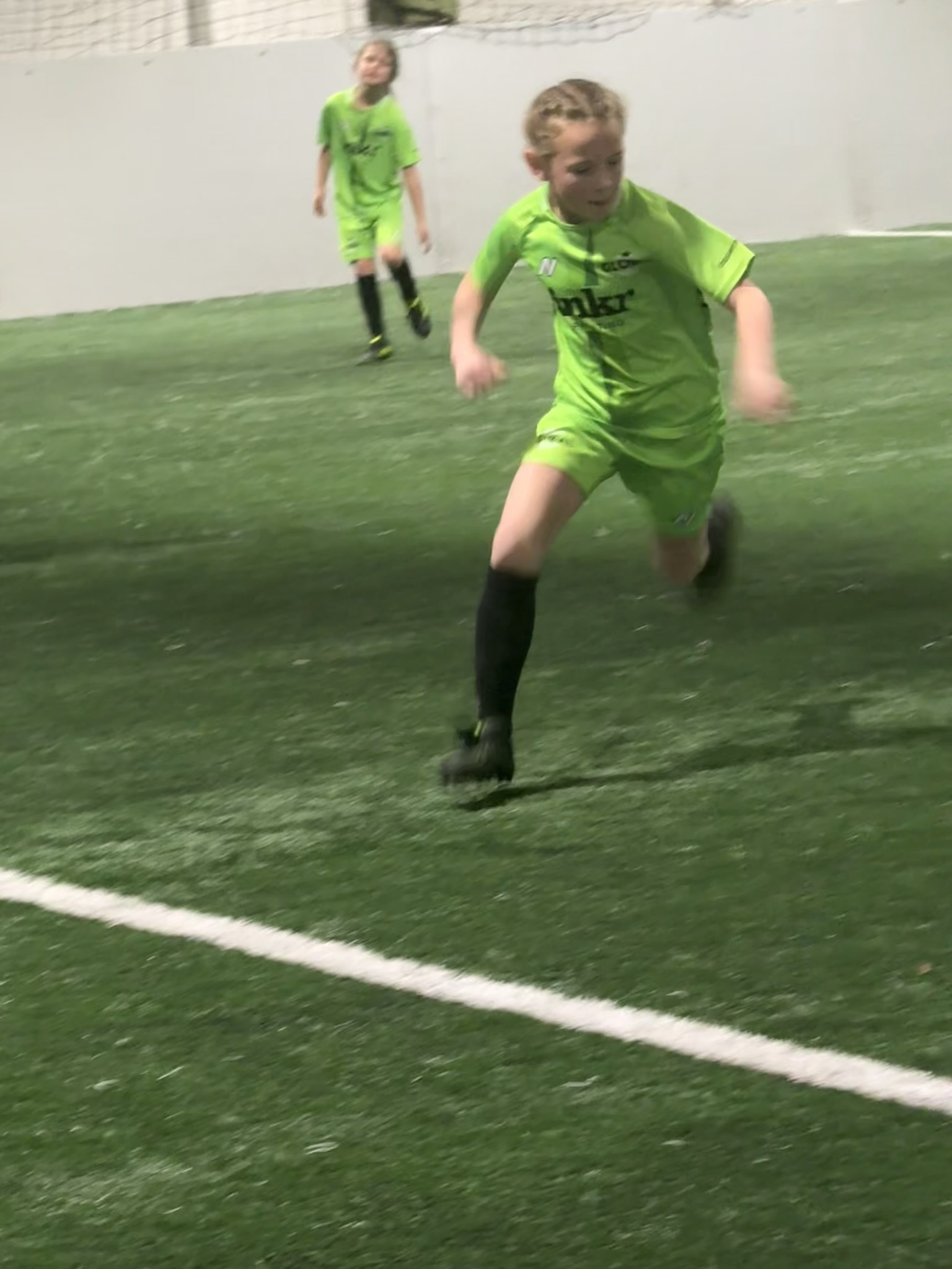 Grace playing indoor soccer in a green jersey